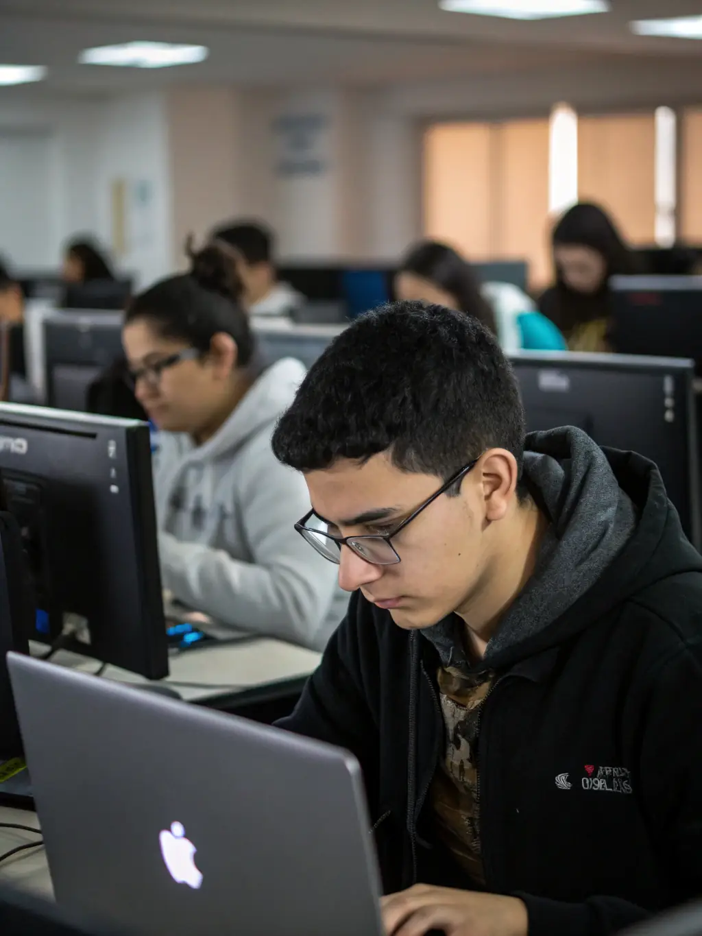 A photograph of a group of teenagers participating in a digital literacy workshop at the library, focusing on coding and online safety.